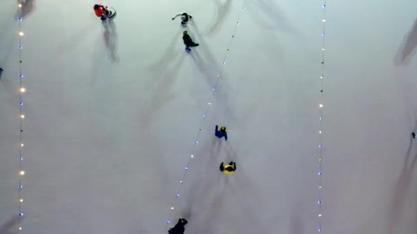 冬の夜景を眺めながら屋外でアイススケートを楽しむ人もいます 発光輝くガーランドランプの照明 下へ下がれ 空中ドローンビュー クリスマスのお祝いの休日のレクリエーション — ストック動画