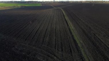 Güneşli bir sonbahar gününde tarla sürmüş tarlaların manzarası. Kara toprakla kaplı toprağın üzerinde uçuyorlar. Toprak toprağa karışıyor. Tarım geçmişi. Kara toprak. Hava aracı görünümü.