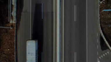Cars driving along highway on autumn sunny day. Automobile road with white markings between agricultural fields. View of cars driving on paved road. Automobile vehicles. Top view. Aerial drone view.