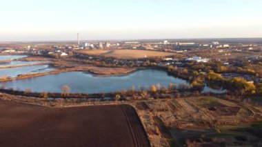 Urban beautiful landscape agricultural plowed fields, lakes for growing fish, gardens, thermal power plant, building industrial area of city on a sunny autumn day. Aerial drone view. Agrarian scenery