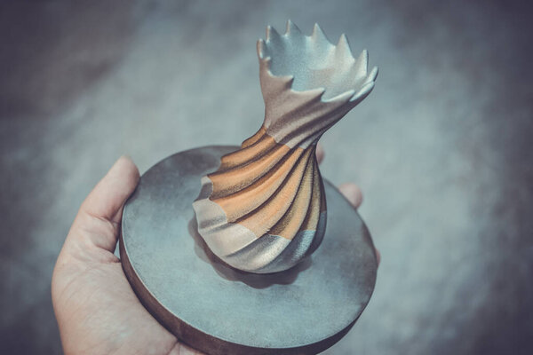 Человек держит объект, напечатанный на металлическом 3D принтере. Объект, отпечатанный в машине лазерного спекания. Современная 3D печать принтера из металлического порошка. Технология прогрессивной аддитивной печати DMLS, SLM, SLS 3d