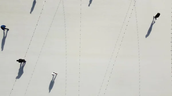 stock image People ride on white ice rink on street and cast long shadows. People skating on sunny winter day. Top view. Aerial drone view. Leisure entertainment vacation weekend holidays activities lifestyle.