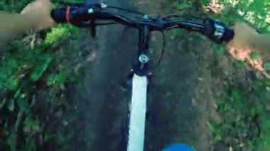 Güneşli bir yaz gününde ormanda kirli bir yolda bisiklet süren bir adam. Ormandaki yeşil ağaçlar arasında bisiklet süren biri. Bakış açısı. Aşırı eğlence, aktif yaşam tarzı etkinliği