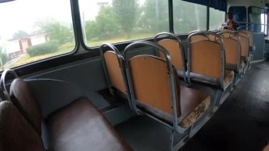 Otobüse binen adam. Koltukta oturan ve şehirde içi boş, otantik bir toplu taşıma otobüsüne binen bir kadın. Otobüsteki kişi. Bakış açısı. Geniş açı. Nakliye aracı hareket ediyor. İçeride Sovyet tarzı otobüs var. İç görünüm