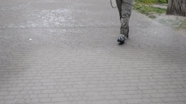 Koruyucu giysili bir adam şehrin kaldırımına antiseptik solüsyon sıkıyor. Koronavirüsü önlemek için sprey kimyasalların dezenfekte edilmesi. Halka açık yerlerde hijyenik önlemler. Koronavirüs salgını