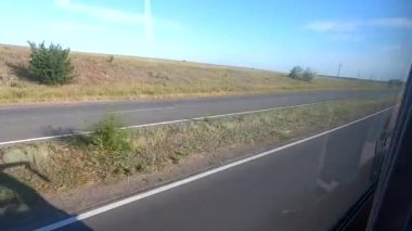 Otobüs penceresinden bak. Tarlalar, ağaçlar, mavi gökyüzü, yol, hareket halindeki bir otobüsün camındaki arabalar. Taşınma seyahati turizm taşımacılık seyahati kavramını kabul et