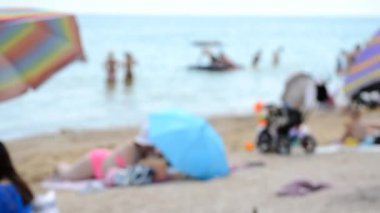 Bulanık arka plan deniz plajı şemsiyeleri insanlar yaz günü. İnsanlar dinleniyor, kumda yatıyor, denizde yüzüyor, çocuklar koşuyor, adam deniz kıyısında yürüyor. Tatil kavramı tatil tatili turizmi eğlencesi