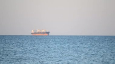 Deniz manzarası, deniz manzarası. Güneşli bir günde denizdeki ufukta büyük bir kargo gemisi tahıl tankeri. Mavi su. Ulaşım, ulaşım, deniz taşımacılığı, kargo taşımacılığı