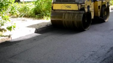 Paver, kaldırım makinesi. Sarı asfalt asfalt asfalt makinesi. Sokakta sıcak siyah asfalt yuvarlıyor..