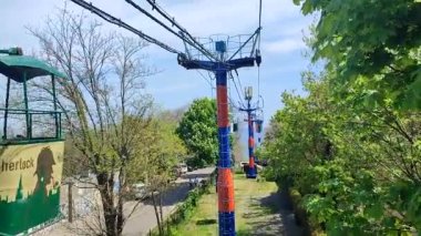 Odessa Ukrayna 7 Mayıs 2023: Güneşli bahar yaz günlerinde şehirde farklı şekillerde boyanmış çok renkli kamaralı kablo. Deniz kıyısındaki ağaçların arasında gezici teleferik. Halat yolu.