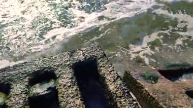 Deniz dalgaları güneşli bir yaz gününde kıyıda eski beton levhalara vurur. Beyaz köpüklü mavi deniz dalgaları. Deniz manzarası işte. Deniz kıyısı kıyısı. Doğal zemin arkaplan