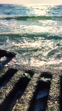 Deniz dalgaları, güneşli yaz gününde eski beton levhaları yener. Beyaz köpüklü mavi deniz dalgaları. Deniz manzarası işte. Deniz kıyısı kıyısı. Doğal arka plan arka plan. Dikey
