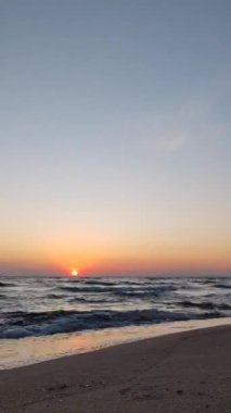 Denizde Gündoğumu Uyanışı. Yuvarlanan deniz dalgaları üzerinde yükselen güneş. Turuncu gökyüzü güneşi, mavi deniz. Deniz suyu sabah ufku. Doğal zemin, doğal zemin. Deniz manzaralı. Yavaş çekim Zaman Kaynağı Dikey