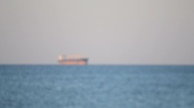 Deniz manzarası, deniz manzarası. Güneşli bir günde denizde ufukta büyük bir kargo gemisi tahıl tankeri görünüyor. Mavi su. Ulaşım, ulaşım, deniz taşımacılığı, deniz taşımacılığı. Bulanık arkaplan
