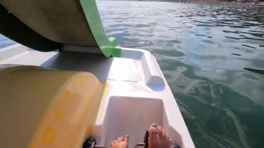Katamaran üzerinde yüzen bir kadın. Ayağıyla pedal çeviren ve güneşli yaz gününde dalgalarla deniz yüzeyinde katamaran üzerinde yüzen biri. Aktif yaşam tarzı eğlence sporu POV