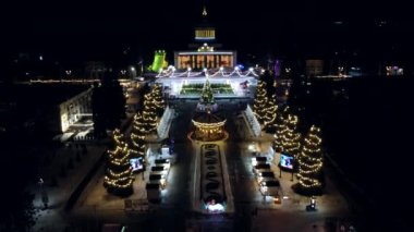 Kyiv, Ukrayna 20 Ocak 2022: Manzara manzarası büyük bina, Noel ağaçları, dönen atlıkarınca ve açık hava buz pateni pisti. Parlak ışık çelenkleri Yeni yıl süslemeleri