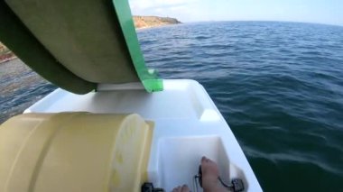Katamaran üzerinde yüzen bir kadın. Ayağıyla pedal çeviren ve güneşli yaz gününde dalgalarla deniz yüzeyinde katamaran üzerinde yüzen biri. Aktif yaşam tarzı eğlence sporu POV
