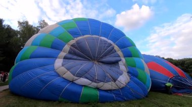 Yerde yatan bir balonu şişirmek. Balon Festivali 'nde büyük mavi balon hava ile şişirilir. Balon havayı dolduruyor. Balon gibi. Eğlence turizmi dinlenme gezisi aktivitesi