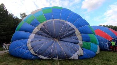 Yerde yatan bir balonu şişirmek. Balon Festivali 'nde büyük mavi balon hava ile şişirilir. Balon havayı dolduruyor. Balon gibi. Eğlence turizmi dinlenme gezisi aktivitesi