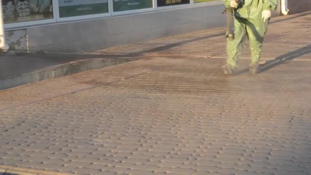 Man Airtight Suit Sprays Disinfecting Liquid Pavement Street City Backdrop — Video