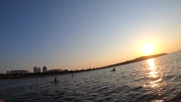 黎明时分 人在Sup板上漂浮着 人们在白色的Sup船上漂浮 在海面上划桨 在日落时分 海浪在近岸飘扬 积极的生活娱乐和体育活动 — 图库视频影像