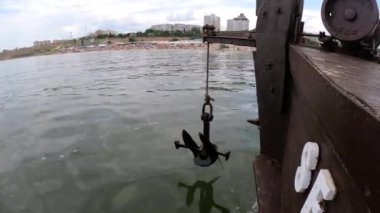 Eski paslı çapa ipte sallanıyor ve denizin yüzeyinde yüzen ahşap bir geminin kıç tarafında sendeliyor. Gemide yelken açmak, gemide yüzmek. Seyahat tatili