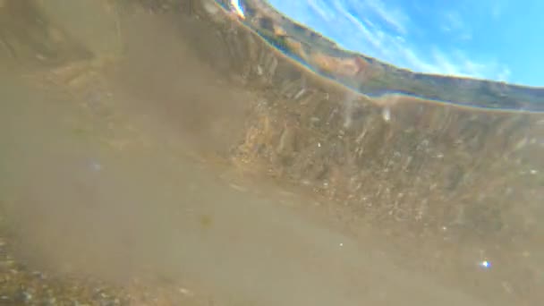 在海滨沙滩上 从透明的水底俯瞰着高山蓝天的海岸 阳光灿烂的夏日 从内部移动海浪 水面上的裂痕 漂浮的水母 自然背景 — 图库视频影像