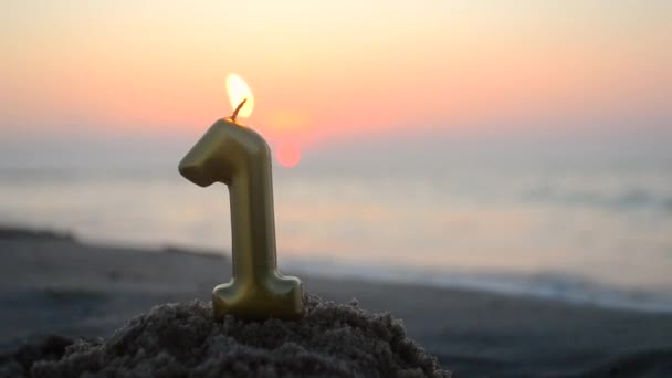 黄金色のパラフィンキャンドルワックスからのナンバーワンは 夜明けの日没の終わりに海の海岸の砂浜で燃焼します パラフィンキャンドルは海の近くで燃える コンセプトホリデー誕生日パーティーお祝い — ストック動画