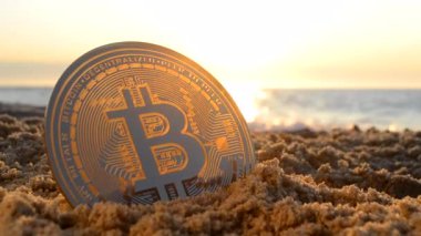 Bitcoin BTS coin in sand near sea waves on sandy beach of sea coast at dawn sunset close-up. Concept cryptocurrency money cryptography cryptocurrencies bitcoins crypto-currencies. Peer-to-peer payment