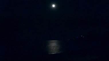 Kara bir gecede denizin su yüzeyinde parlayan beyaz ay ve ay yolu. Ay ışığı. Doğa arkaplanı. Sakin, her gece karanlık, sakin ay ışığı. Sahil kıyısı. Doğal arkaplan.