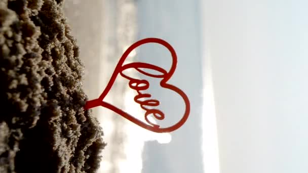 在阳光明媚的夏日里 沙滩上的爱在沙滩上的近照 人形心形爱情背景海浪 恋爱关系的浪漫概念 — 图库视频影像