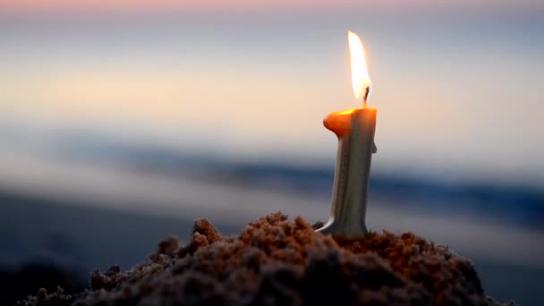 새벽에 파도의 해안의 해변에 모래에 하나의 모양의 파라핀 양초를 태우고 — 비디오
