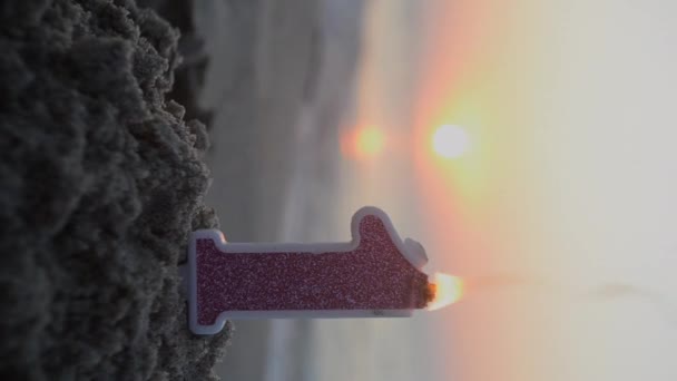 日落时分 在海滨的沙滩上 用粉红闪烁着的石蜡蜡烧成的一个数字 — 图库视频影像