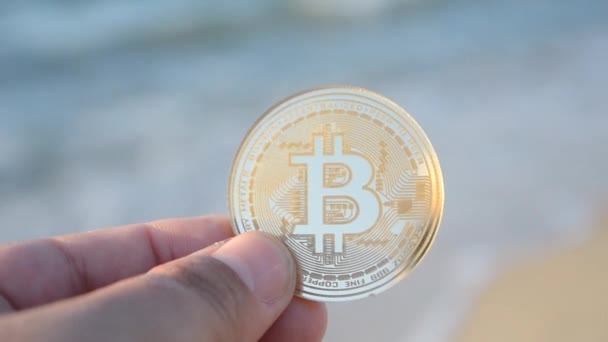 Человек Держащий Руке Монету Bitcoin Btc Фоне Морских Волн Песчаном — стоковое видео