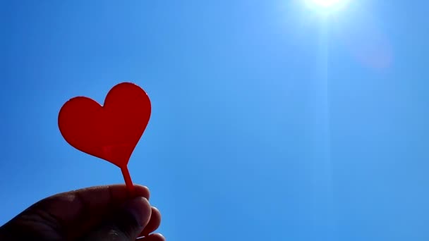 夏日阳光灿烂 蓝天的背景下 手握红心棒的人 情人节的浪漫爱情庆祝活动 — 图库视频影像