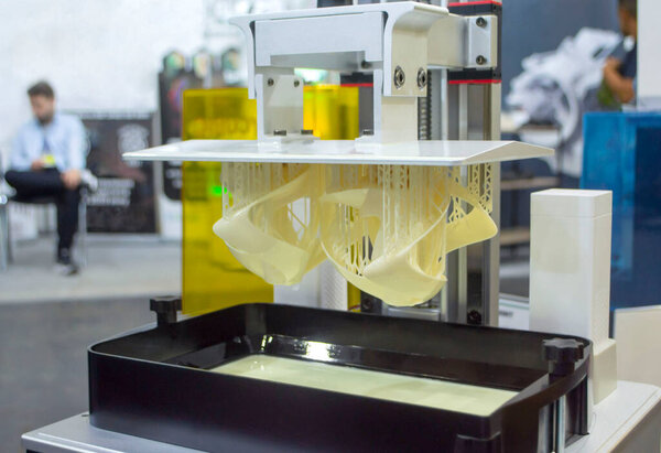 Printed models on 3D printer close-up. Objects printed on photopolymer sla 3D printer from liquid photopolymer resins on printing platform. Modern progressive additive technology. 3D printer printing