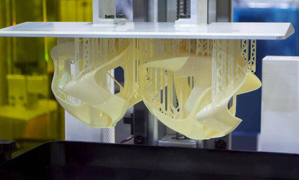 Printed models on 3D printer close-up. Objects printed on photopolymer sla 3D printer from liquid photopolymer resins on printing platform. Modern progressive additive technology. 3D printer printing
