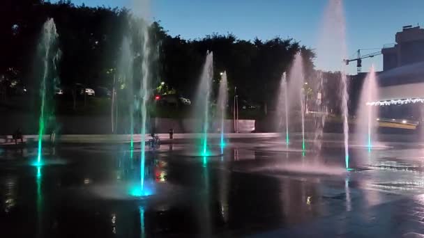 灿烂的灯光照亮了行人专用的地面喷泉 在城市里 大型的公共街道喷泉被五彩缤纷的灯光照亮 水从高处涌出 从高处滚落下来 — 图库视频影像