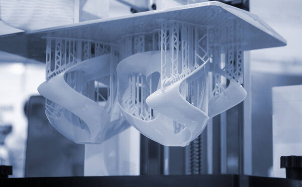 Printed models on 3D printer close-up. Objects printed on photopolymer sla 3D printer from liquid photopolymer resins on printing platform. Modern progressive additive technology. 3D printer printing
