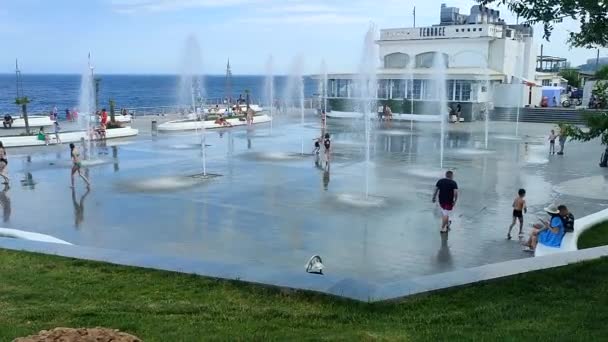 2023年7月2日 オデッサ ウクライナ 晴れた夏の日に海の近くの歩行者地下噴水から水のジェットの下で走る子供たち 大きな公共の街の噴水と街の広場に子供を飛ばす — ストック動画