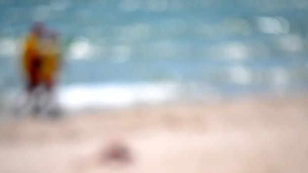 晴れた夏の日に海岸の砂浜に沿って歩く制服の2つのライフガード 晴れた夏の日に海浜の砂浜の波海岸 水面海岸の抽象的な眺め バックグラウンド — ストック動画