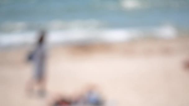 夏天阳光灿烂的日子 妇女在海滨沙滩上散步 在阳光明媚的夏日 海滩上的沙滩波涛汹涌 摘要近岸水面摘要 模糊的背景 — 图库视频影像