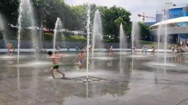 Odessa Ukrayna, 2 Temmuz 2023: Güneşli bir yaz gününde yaya çeşmesinden su fışkırtan çocuklar. Şehir meydanında büyük halk çeşmeleri ve su sıçratan çocuklar.