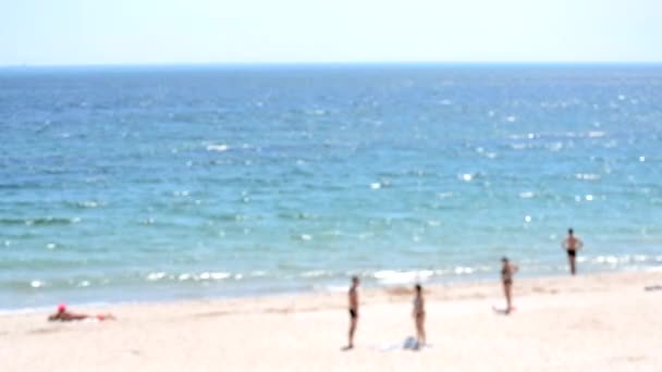青い海の近くの海岸の砂浜に立って休んで日光浴をする多くの人々は 晴れた夏の日には日光の白いスポットがあります 海岸と海岸の抽象的なビュー バックグラウンド — ストック動画