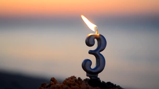 日落时分 在靠近海浪水面的海滨沙滩上 燃烧着形状为3号的石蜡蜡 庆祝浪漫假期的新年庆祝会 — 图库视频影像