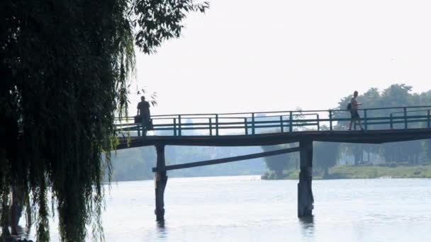 Černé Siluety Lidí Muž Kole Kráčející Starém Dřevěném Mostě Přes — Stock video