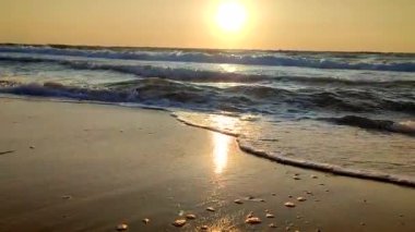 Fırtınalı deniz. Gün batımında ve şafakta denizde beyaz köpüklü büyük dalgalar. Mavi deniz, turuncu kırmızı gökyüzü, güneş. Sahil kıyısı kıyı şeridi. Doğal zemin arka plan fırtınası Alt görünüm