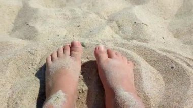 Ayakları kumda kazı yapan bir kadın. Sıcak yaz gününde kumsalda ayaklarını kuru kuma gömme oyunu oynayan biri. Tatil tatili, tatil, dinlenme, turizm...