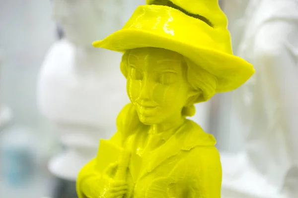Yellow model printed on a 3D printer from melted plastic on a blue surface. Yellow object printed by a 3D printer on table. Concept new modern innovation printing technology