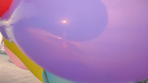 夜明けと日没に海の背景にある多くのカラフルな膨脹可能なボール 日没の日の出に海の近くで手元で多彩な風船で遊んでいる人 ボールを通して輝く太陽 エンターテインメントの楽しみ — ストック動画